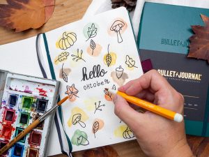 Monatsdeckblatt für Oktober in einem Bullet Journal von LEUCHTTURM1917. Das Motiv: gezeichnete Herbstmotive in Aquarell-Farbklecksen. 