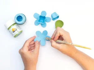 Jemand malt verschiedene, aus einem Eierkarton geschnittene Formen für eine Blüte mit Acrylfarbe an. Foto: Johanna Rundel