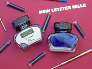 Auf einer roten Dokumentenmappe mit der Aufschrift „Mein letzter Wille“ liegen zwei Tintenfässer sowie zahlreiche Tintenpatronen von Faber-Castell. Foto: Johanna Rundel