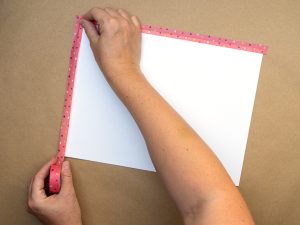 Jemand klebt eine weißes Blatt Papier mit Washitape auf einen mit Packpapier bezogenen Tisch. Foto: Johanna Rundel